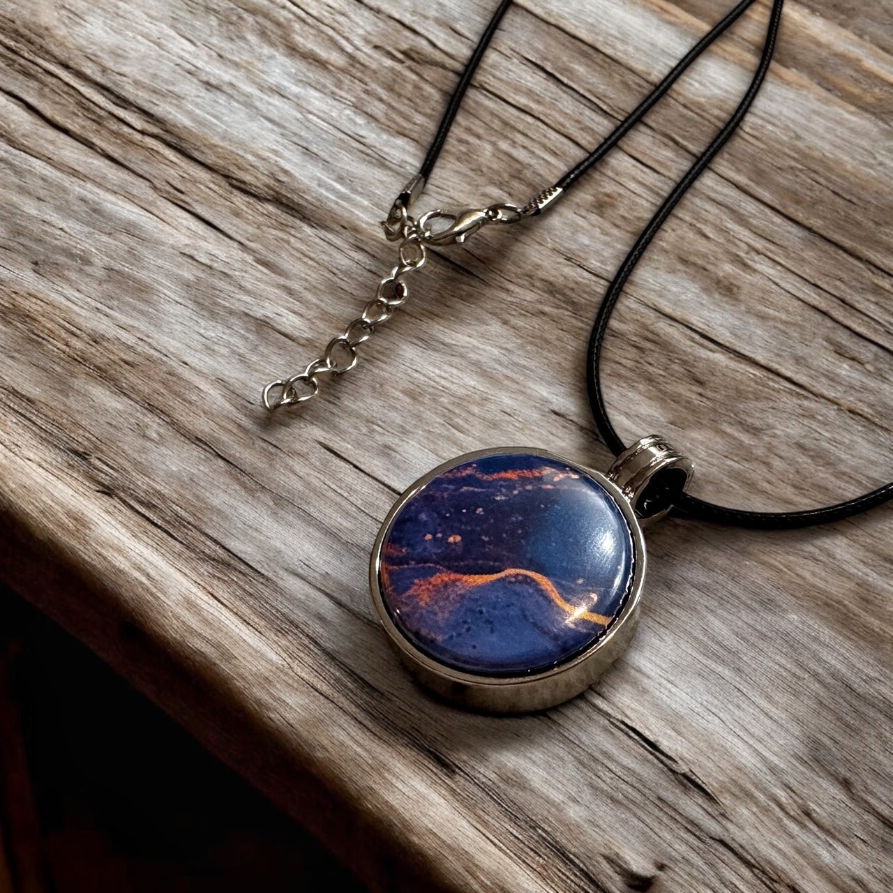 Custom designed 1" button pendant necklace, personalized with unique designs, initials, or symbols for a unique jewelry piece to match any outfit or occasion. Shows blue marble texture and the clasp ends of the necklace