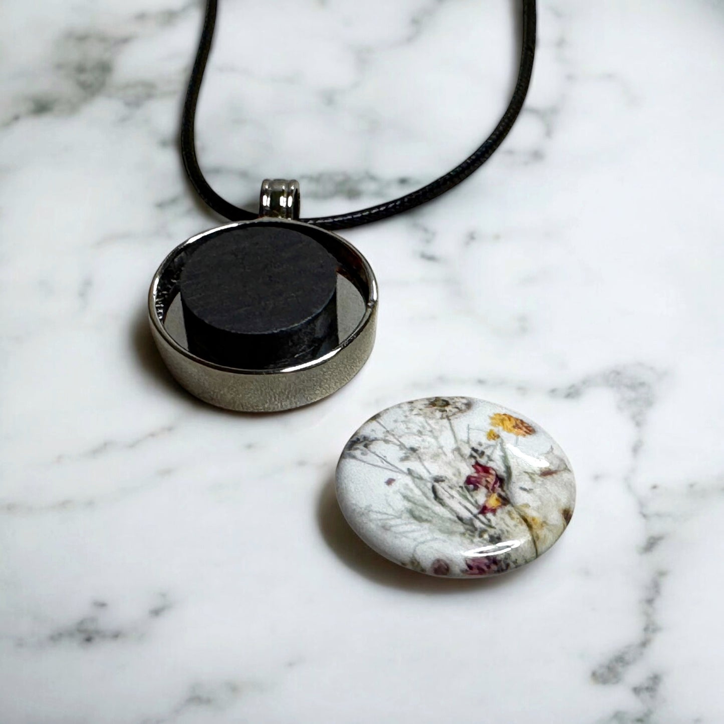Custom designed 1" button pendant necklace, personalized with unique designs, initials, or symbols for a unique jewelry piece to match any outfit or occasion. Sample of the button detached to show the strong ceramic magnet inside the pendant that secures the design to the silver