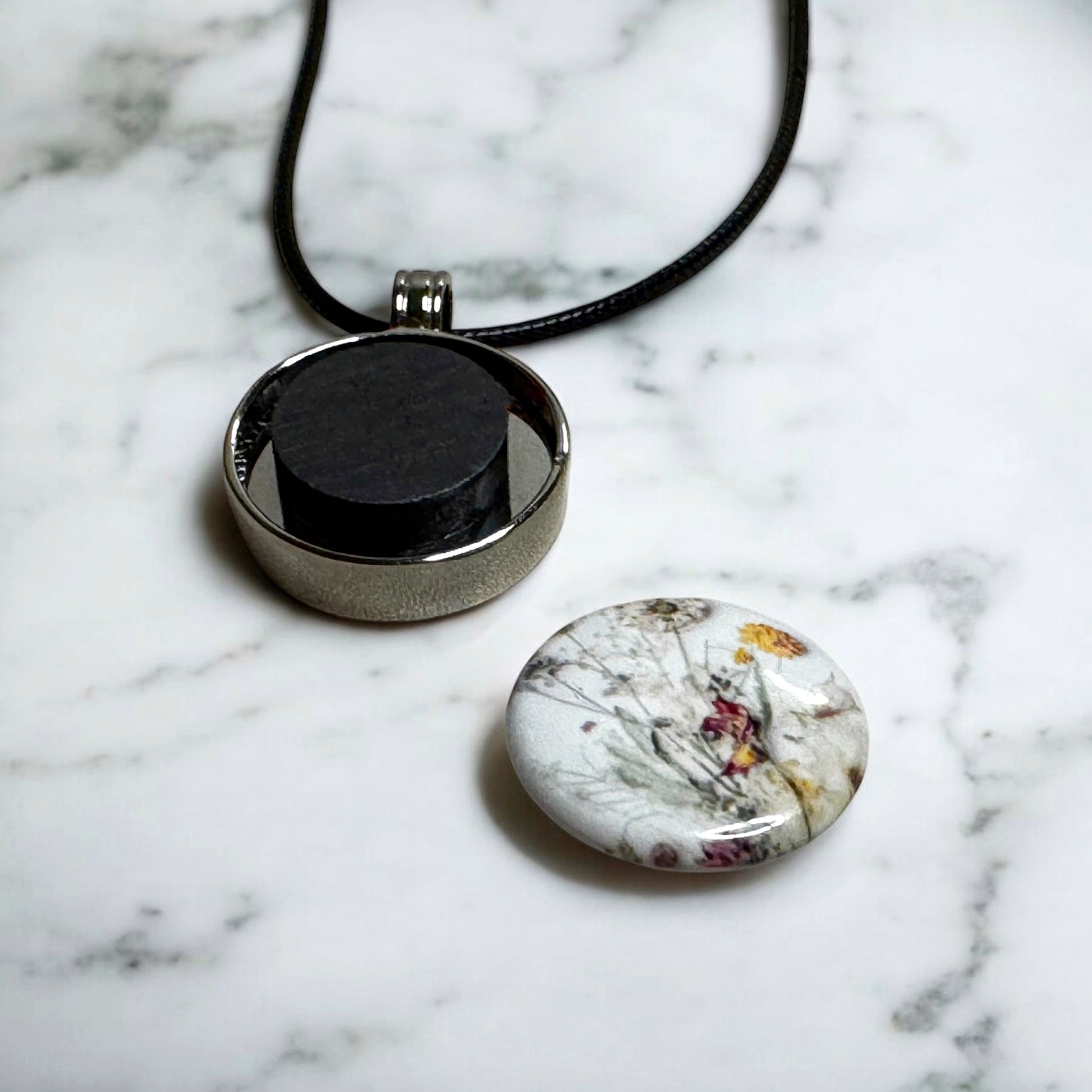 Custom designed 1" button pendant necklace, personalized with unique designs, initials, or symbols for a unique jewelry piece to match any outfit or occasion. Sample of the button detached to show the strong ceramic magnet inside the pendant that secures the design to the silver